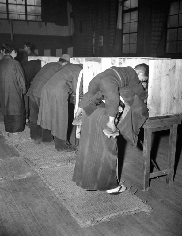 A-Japanese-woman-carries-her-son-on-her-back-as-she-marks-her-ballot-in-Tokyo-792x1024